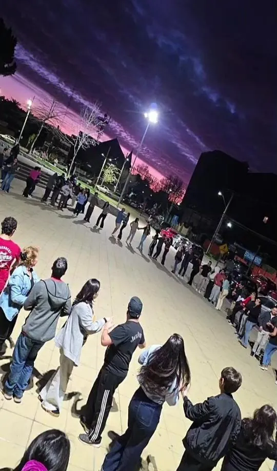 Parejas formando una gran rueda de casino en una plaza al atardecer